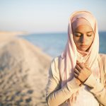 Humble muslim woman praying on the beach.Spiritual religious woman