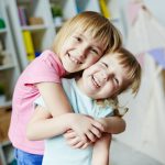 Affectionate girl embracing her laughing sister