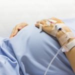 Asian Pregnant Woman patient is on drip receiving a saline solution on bed VIP room at hospital.