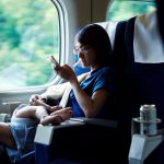 Mother using smartphone while breastfeeding on train